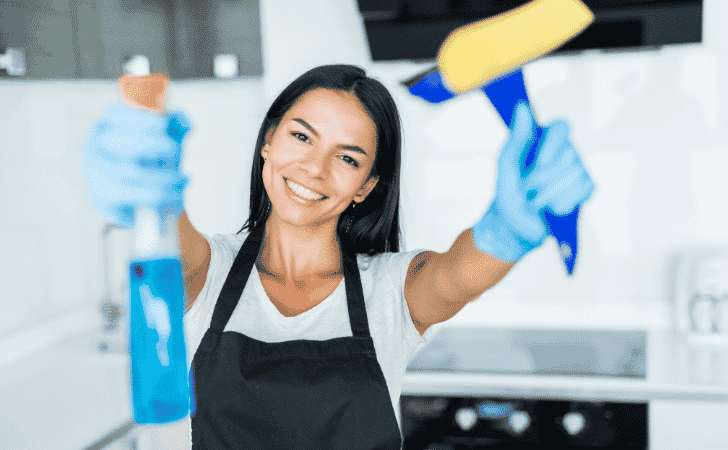 smiling domestic cleaner holding cleaning products