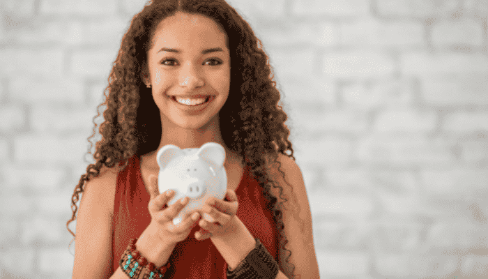 teenage girl smiling and holding a white piggy bank