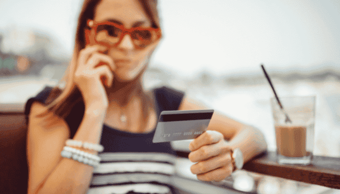 woman talking on the phone with a credit card in her hand