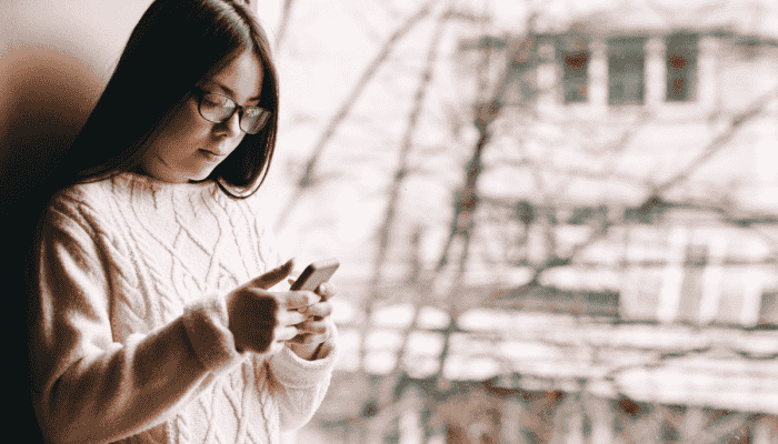 sad girl texting at window