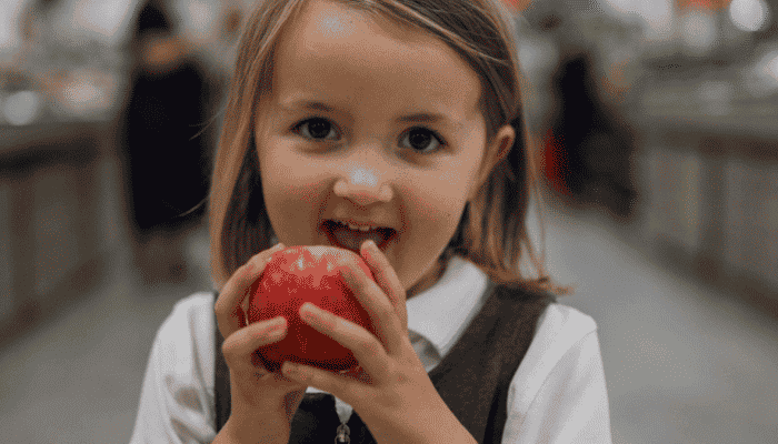 young girl holding an apple in her hands about to eat it