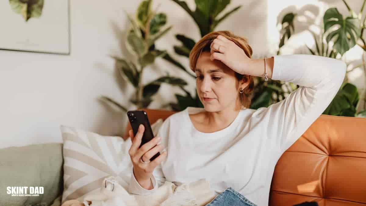 Checking a UK bank statement on a phone to spot forgotten subscriptions.