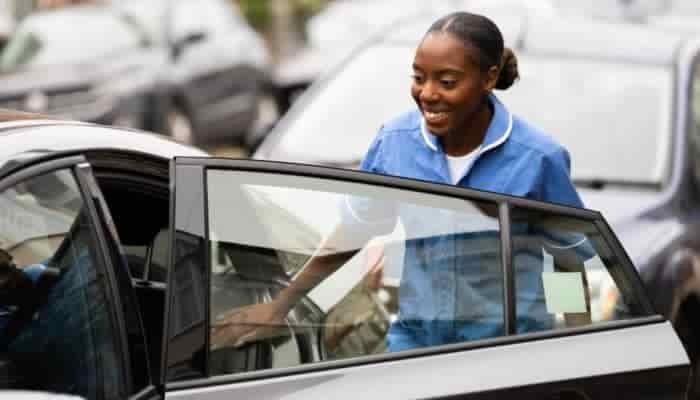 NHS worker opening a car passenger door.
