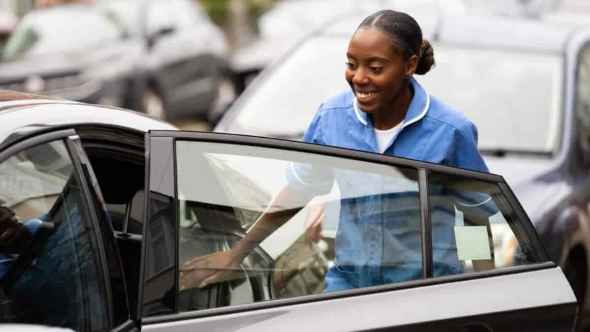 NHS worker opening a car passenger door.