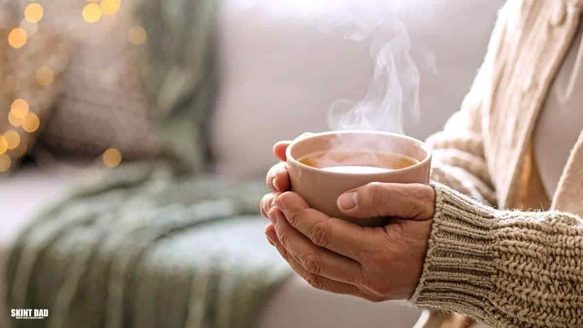 Hands holding a warm mug indoors to show simple ways to stay warm in winter.
